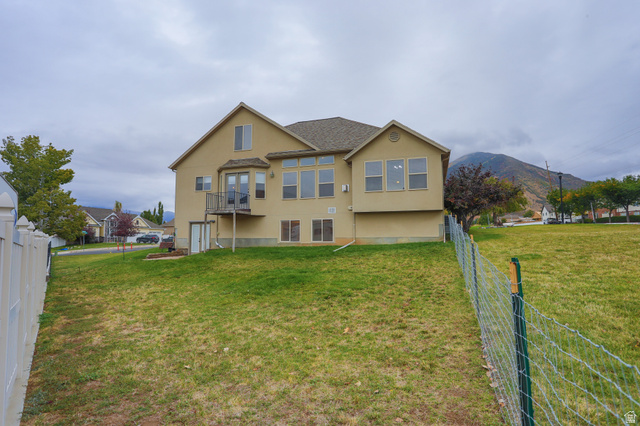 426 Deer Hollow Road Tooele, UT 84074 - Photo 32 of 37 Rear view of house featuring stucco siding, a fenced backyard, a mountain view, and a balcony
