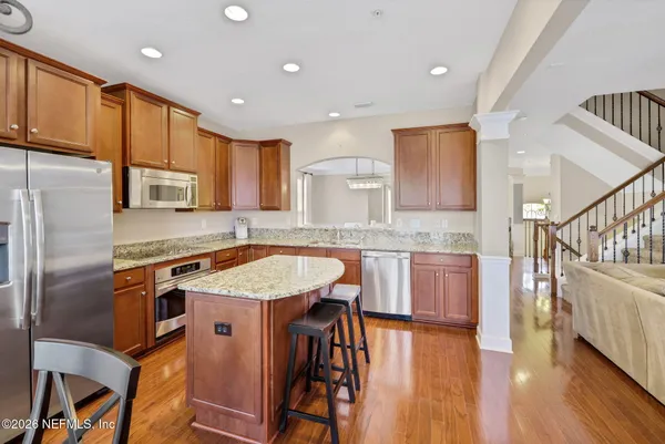 a kitchen with stainless steel appliances granite countertop a stove a refrigerator a kitchen island a table and chairs in it