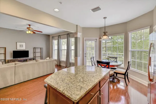 a kitchen with stainless steel appliances granite countertop a stove a refrigerator a sink a dining table and chairs with wooden floor