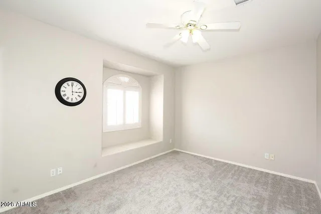 an empty room with a window and a fan