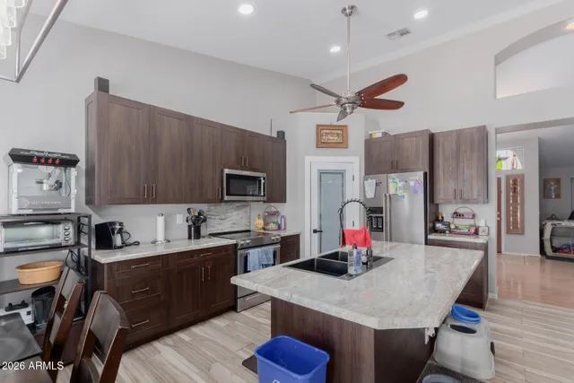 a kitchen with stainless steel appliances kitchen island granite countertop a sink dishwasher a stove a refrigerator a microwave oven with cabinets and wooden floor
