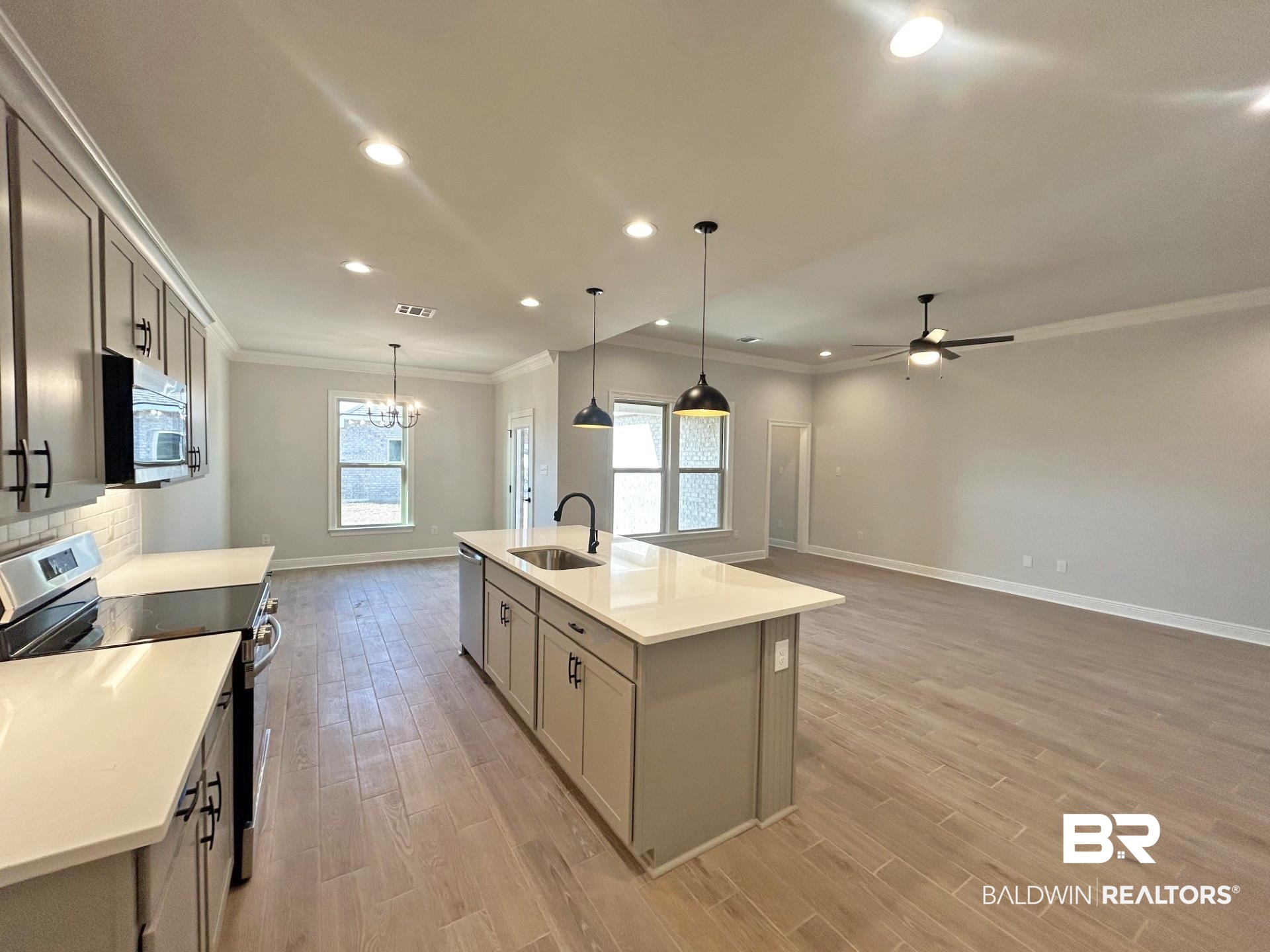 825 Sumter Loop Foley, AL 36535 - Photo 20 of 21 Kitchen featuring appliances with stainless steel finishes, open floor plan, crown molding, hanging light fixtures, and a kitchen island with sink