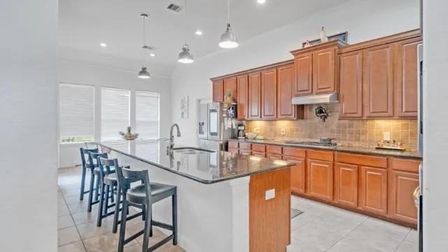 a kitchen with kitchen island granite countertop a table chairs sink and cabinets