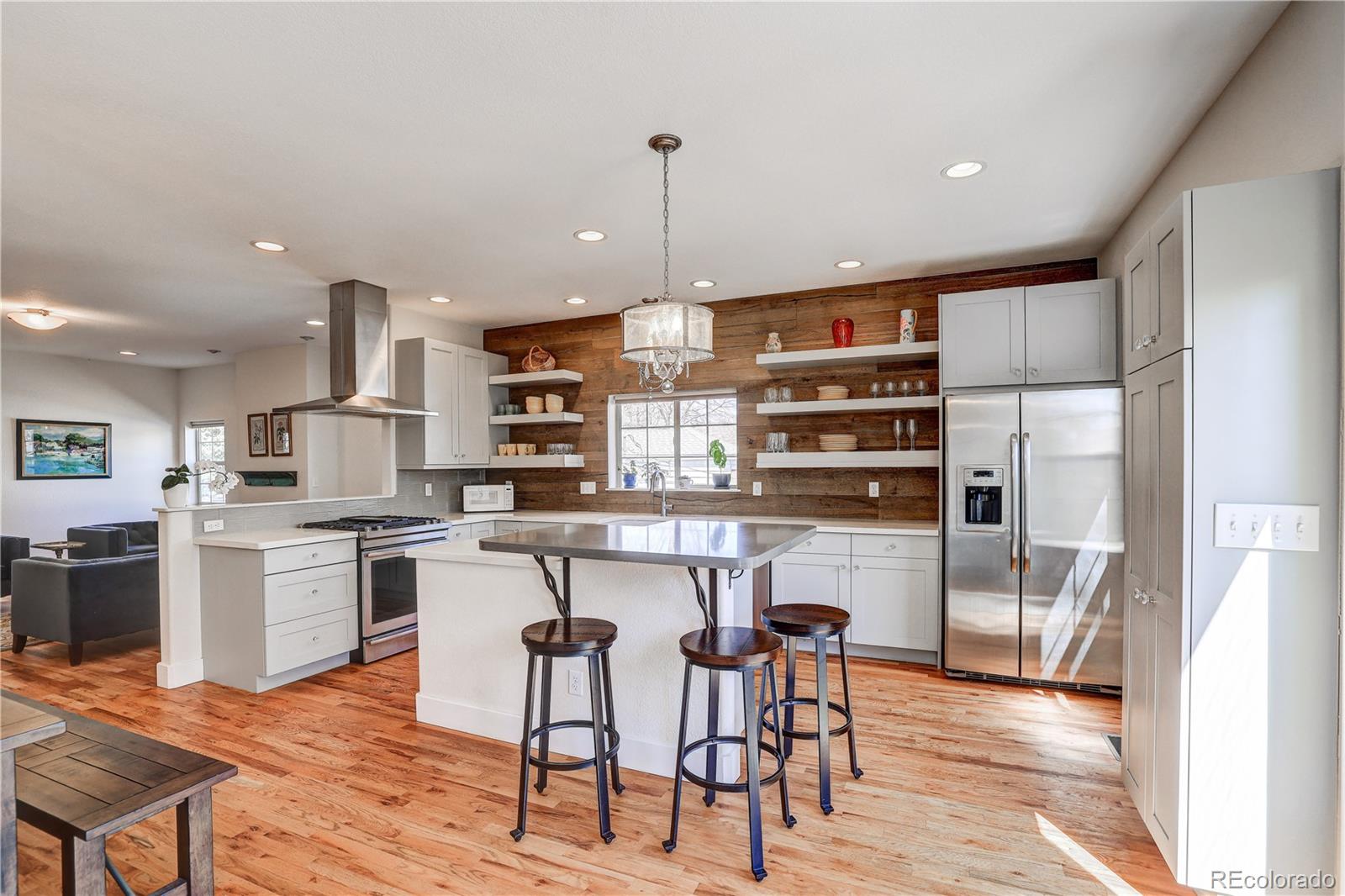 4530 Quitman Street Denver, CO 80212 - Photo 17 of 40 a kitchen with stainless steel appliances kitchen island granite countertop a table chairs in it and wooden floors