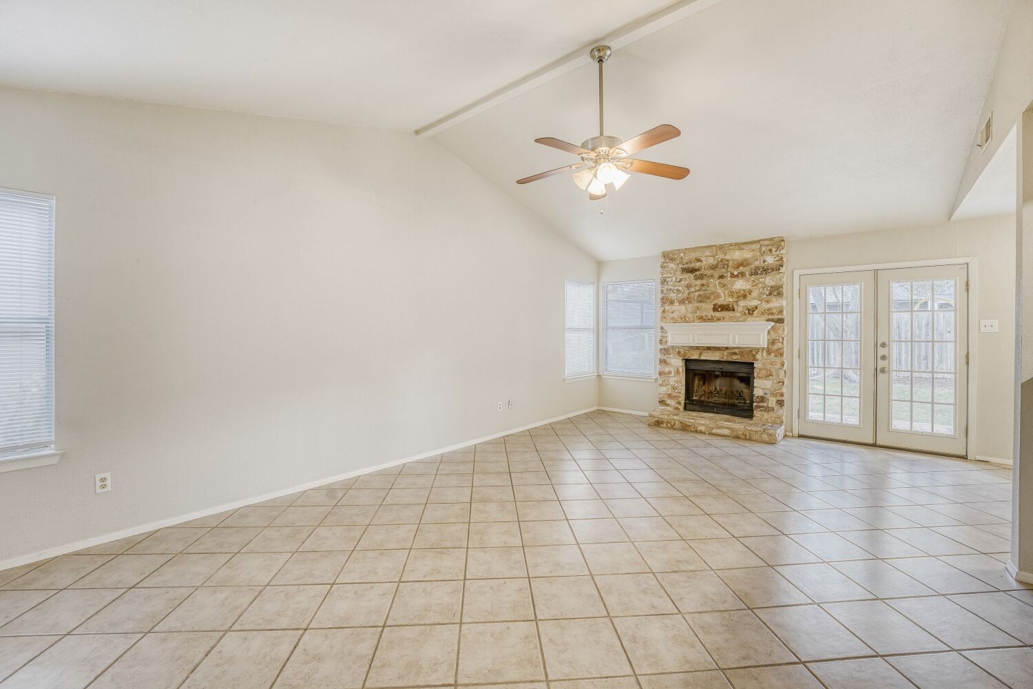 9100 Wagtail Drive Austin, TX 78748 - Photo 4 of 23 french doors, a stone fireplace, a ceiling fan, and hard tile. Now imagine your furniture here.