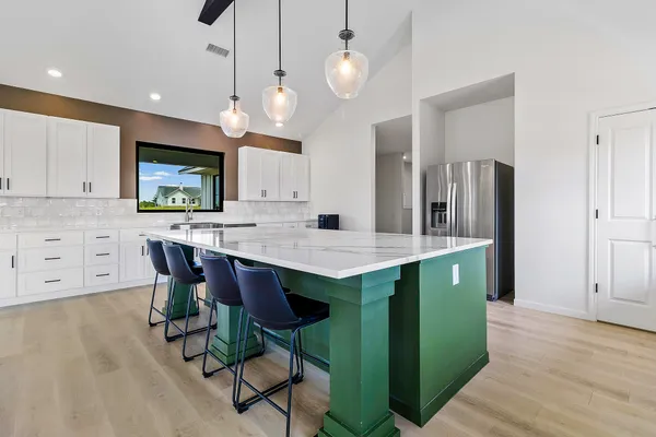 a open kitchen with stainless steel appliances granite countertop a refrigerator a sink dishwasher a dining table and chairs with wooden floor