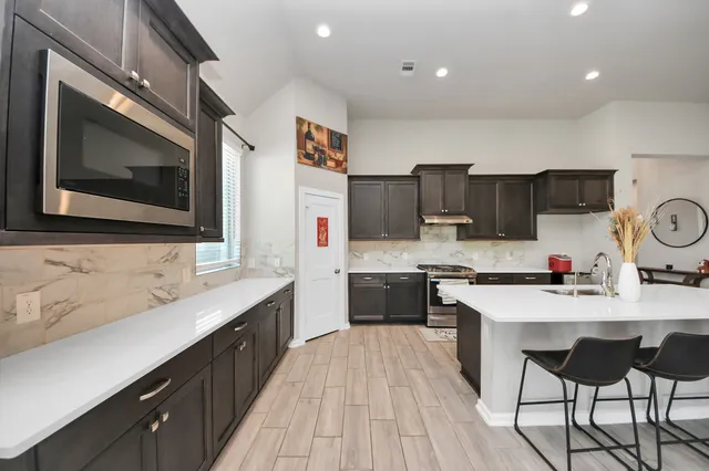 a view of a kitchen counter top space with stainless steel appliances wooden floor and windows