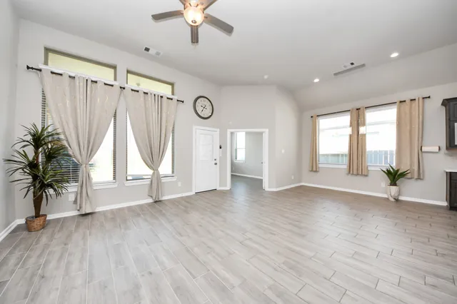 a view of empty room with wooden floor and windows