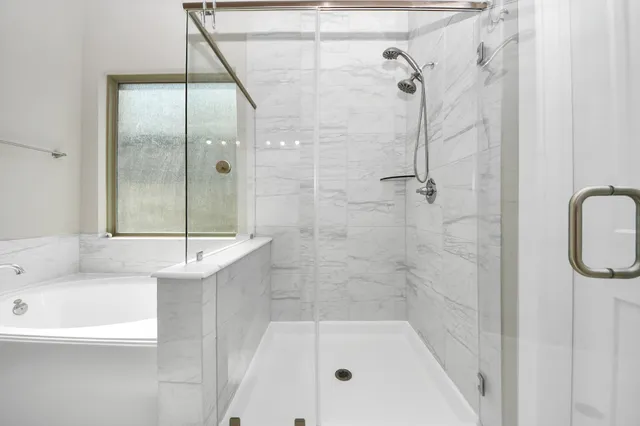 a spacious bathroom with a tub sink shower and mirror