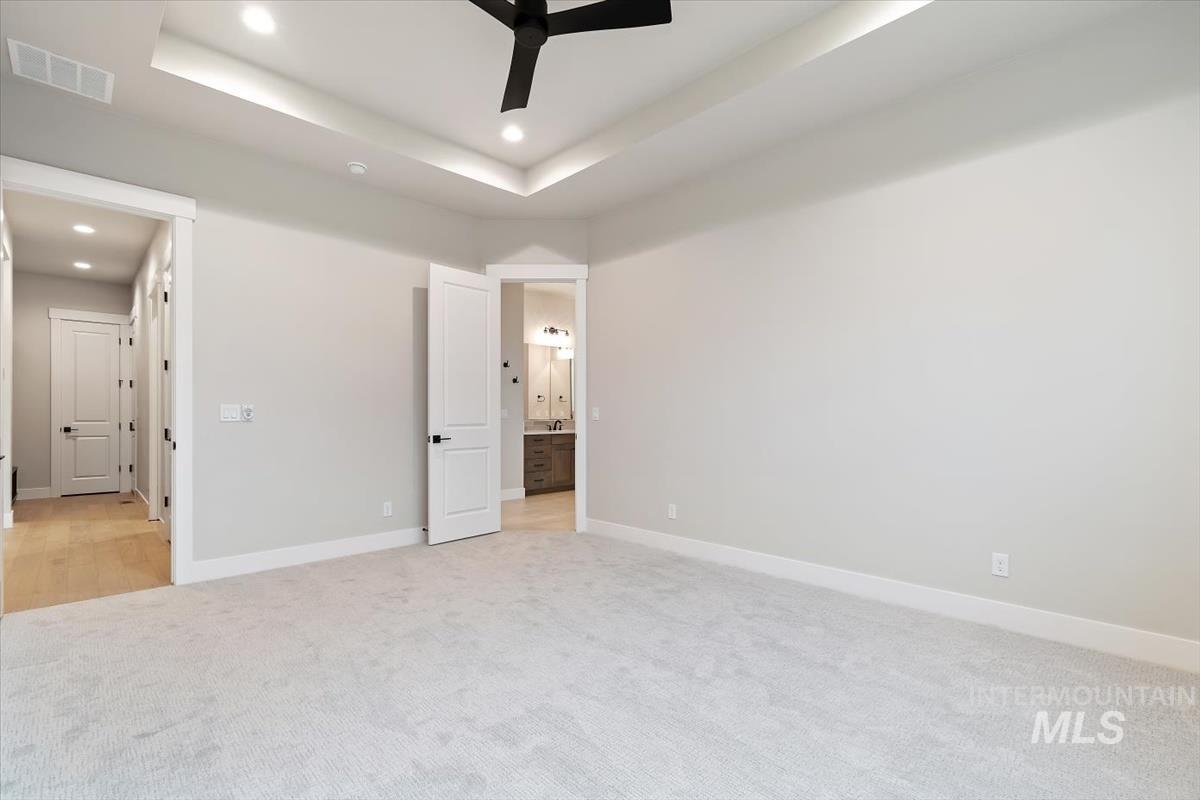 2147 East Blakehurst Avenue Kuna, ID 83634 - Photo 20 of 43 Unfurnished bedroom with light colored carpet, recessed lighting, a tray ceiling, ensuite bath, and ceiling fan