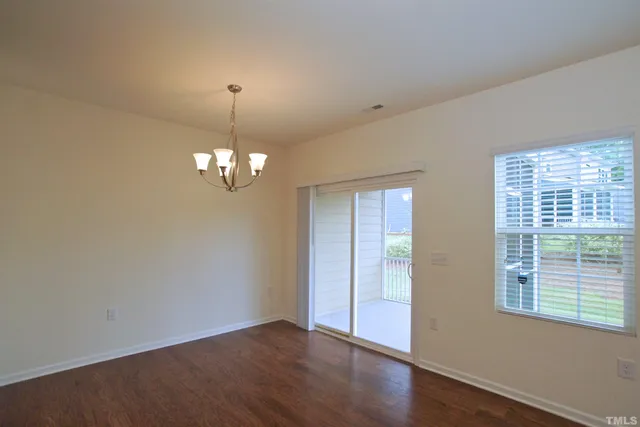 a view of an empty room with wooden floor and windows