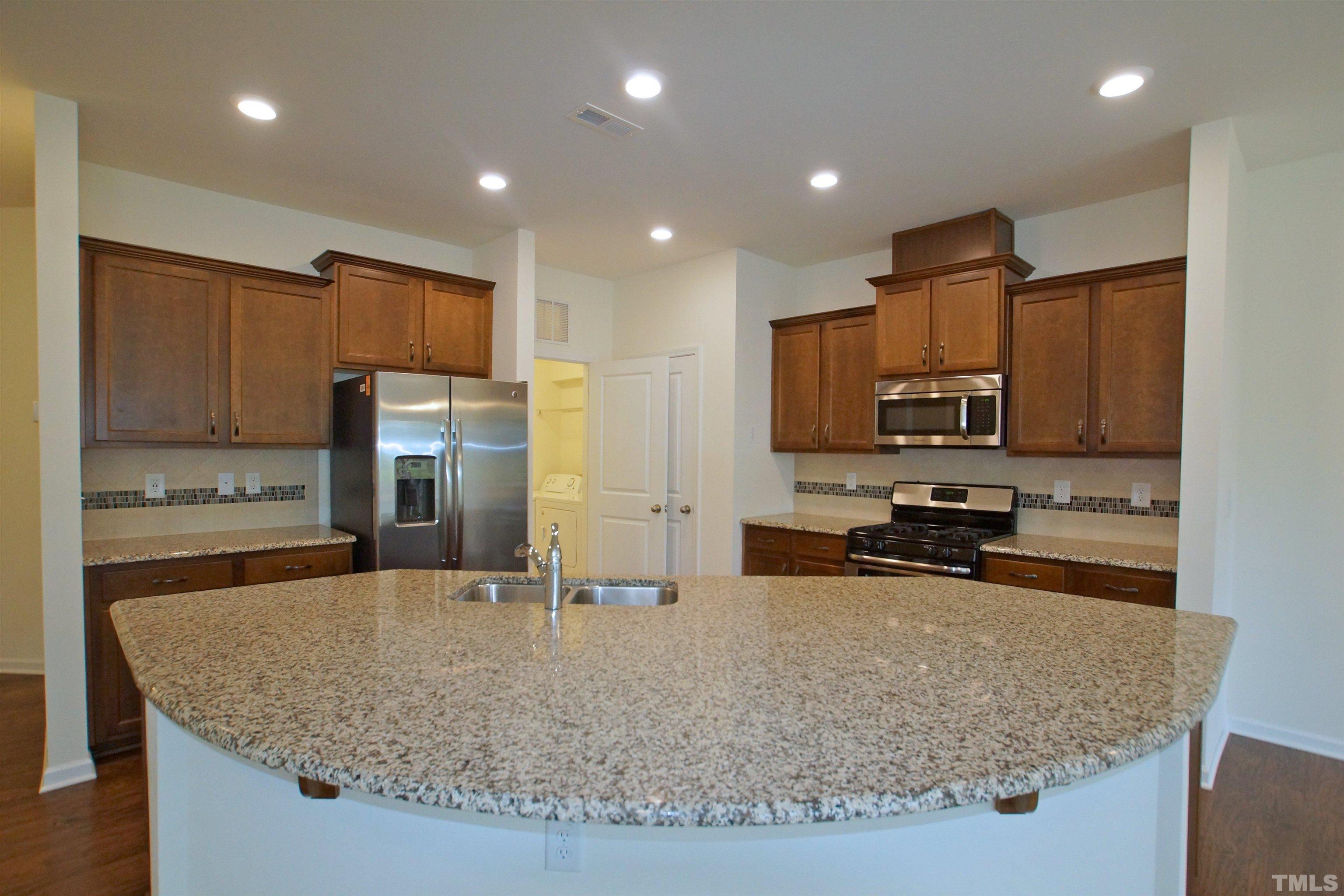 1140 Lookout Ridge Road Apex, NC 27502 - Photo 7 of 22 a kitchen with stainless steel appliances granite countertop a sink stove and refrigerator
