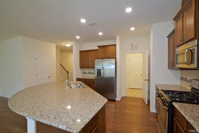a kitchen with stainless steel appliances granite countertop a sink refrigerator and cabinets