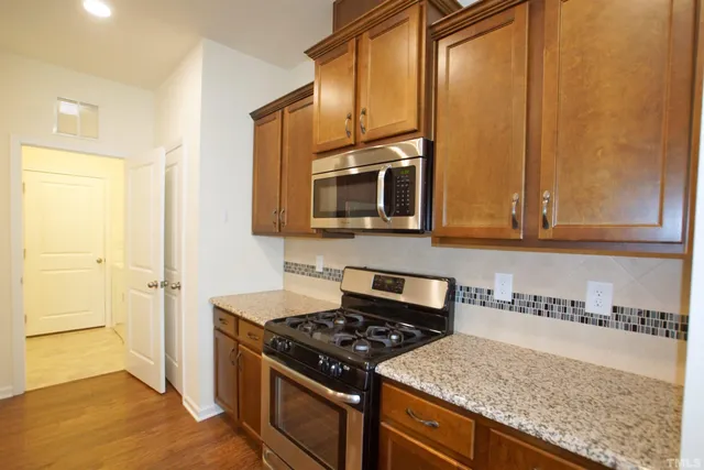 a kitchen with stainless steel appliances granite countertop a stove a sink and a microwave