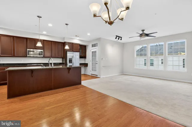 a large kitchen with stainless steel appliances kitchen island granite countertop a refrigerator a stove a sink and a microwave