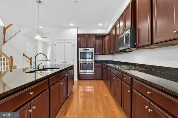 a large kitchen with stainless steel appliances granite countertop a stove a sink dishwasher and a microwave oven with large wooden cabinets