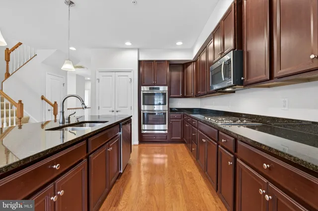 a large kitchen with stainless steel appliances granite countertop a stove a sink dishwasher and a microwave oven with large wooden cabinets