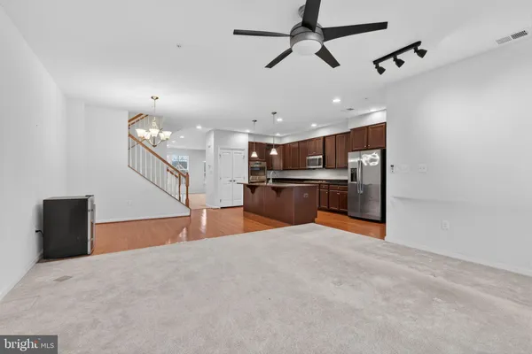 a large kitchen with stainless steel appliances kitchen island granite countertop a refrigerator a stove and a sink with wooden floor