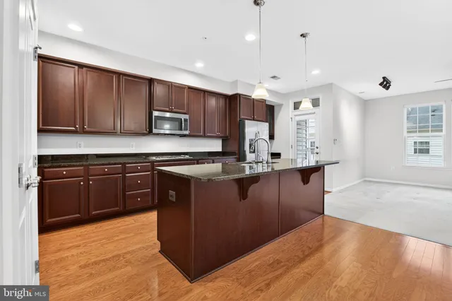 a kitchen with stainless steel appliances granite countertop wooden cabinets a refrigerator a sink and a stove