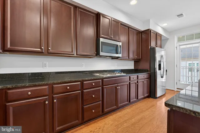 a kitchen with stainless steel appliances granite countertop wooden cabinets a refrigerator and a sink