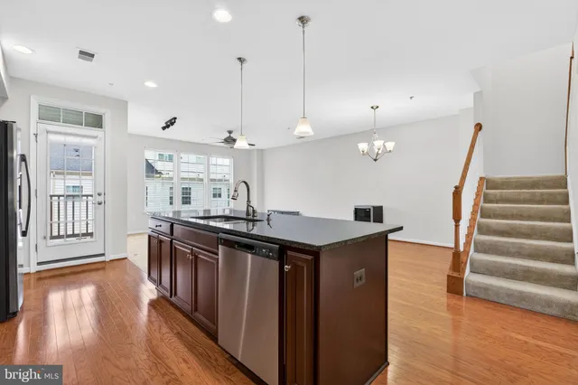 a kitchen with stainless steel appliances granite countertop a sink a stove and a wooden floor