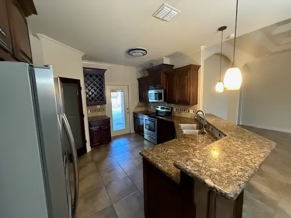 a kitchen with granite countertop kitchen island stainless steel appliances a refrigerator sink and stove