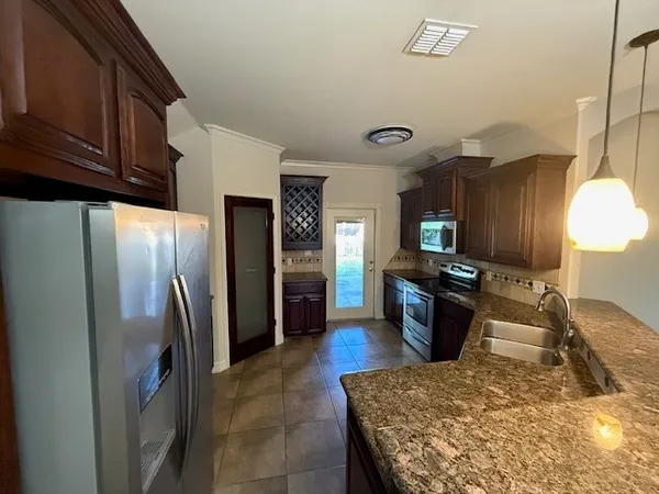 a kitchen with stainless steel appliances granite countertop a refrigerator a stove and a sink