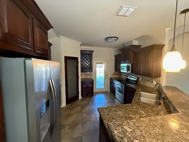 a kitchen with stainless steel appliances granite countertop a refrigerator a stove and a sink