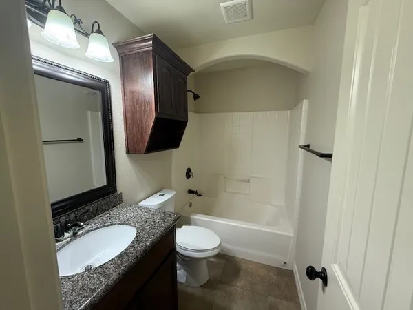 a bathroom with a granite countertop sink toilet mirror and shower