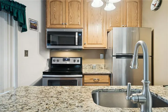 a kitchen with stainless steel appliances granite countertop a refrigerator a stove and a sink