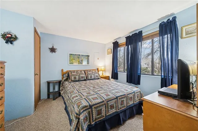 a bedroom with a bed table and flat screen tv