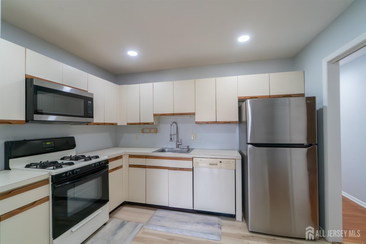 166 Hidden Hollow Court Edison, NJ 08820 - Photo 10 of 36 a kitchen with a refrigerator a microwave a sink and cabinets