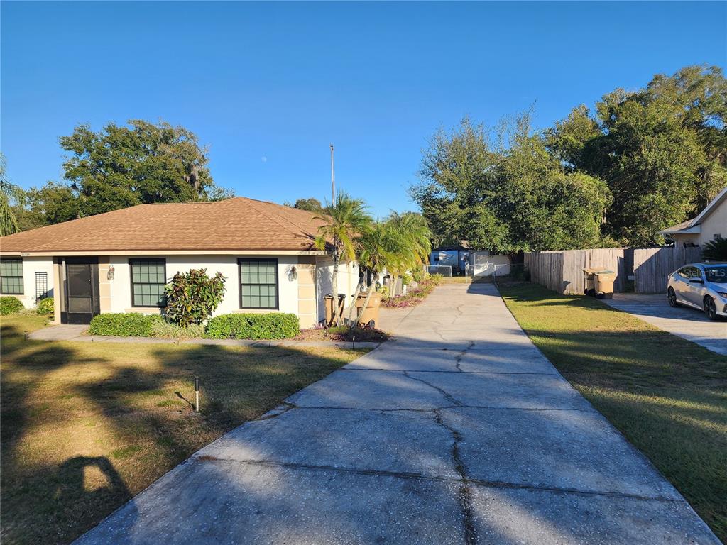 11759 Oswalt Road Clermont, FL 34711 - Photo 9 of 24 a view of a white house with a yard plants and large tree