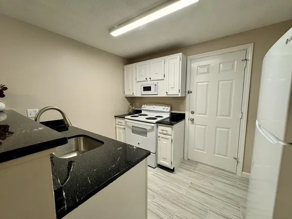 a kitchen with granite countertop white cabinets and white appliances