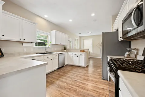 a kitchen with a sink white cabinets and white appliances