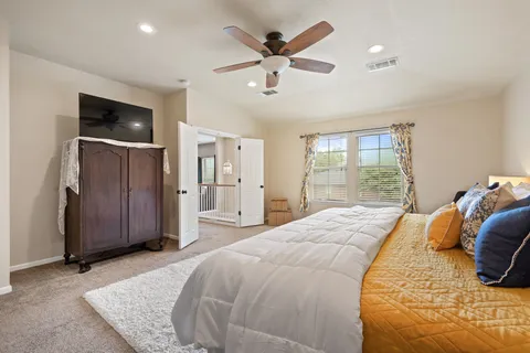 a spacious bedroom with a large bed a flat tv screen and dresser