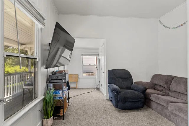 a living room with furniture a flat screen tv and next to a window