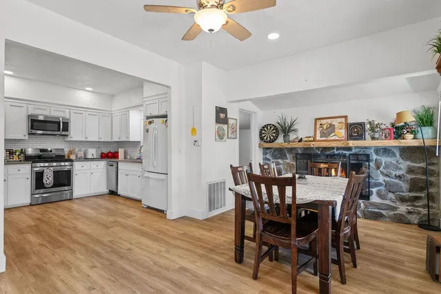 a kitchen with stainless steel appliances granite countertop a dining table chairs refrigerator and microwave