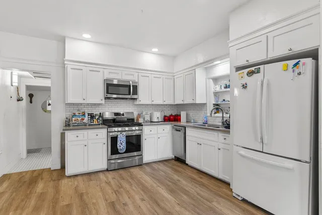 a kitchen with white cabinets and white appliances
