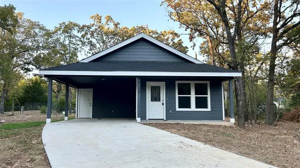 a view of a house with a yard potted plants and a large tree