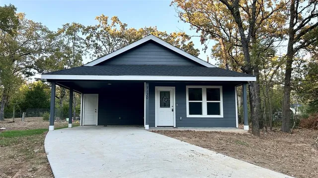 a view of a house with a yard potted plants and a large tree