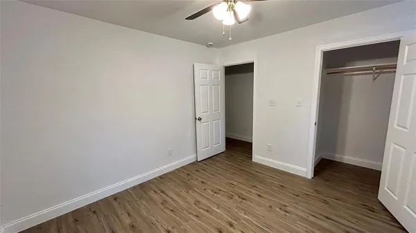 an empty room with wooden floor and closet area