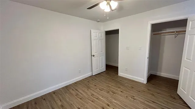 an empty room with wooden floor and closet area