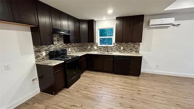 a kitchen with stainless steel appliances granite countertop wooden cabinets and a wooden floors