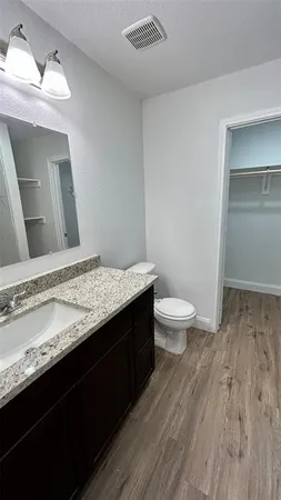 a bathroom with a granite countertop sink a toilet and a mirror