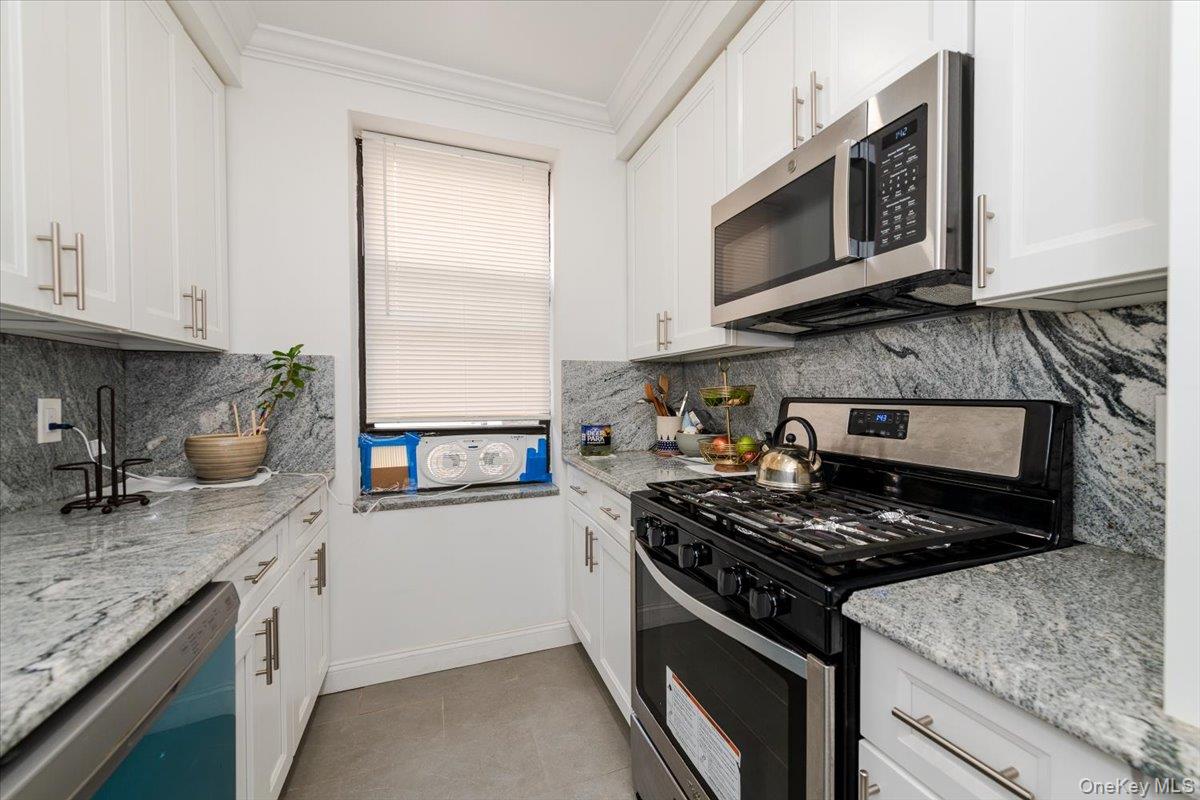 37-21 80th Street, Unit 4H Queens, NY 11372 - Photo 6 of 12 a kitchen with stainless steel appliances granite countertop a stove microwave and sink