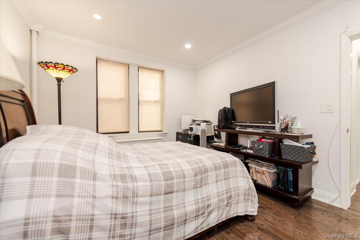 37-21 80th Street, Unit 4H Queens, NY 11372 - Photo 9 of 12 a bedroom with a bed and a flat screen tv
