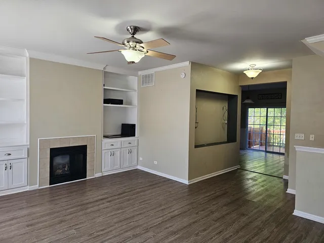 a view of an empty room with wooden floor and a fireplace