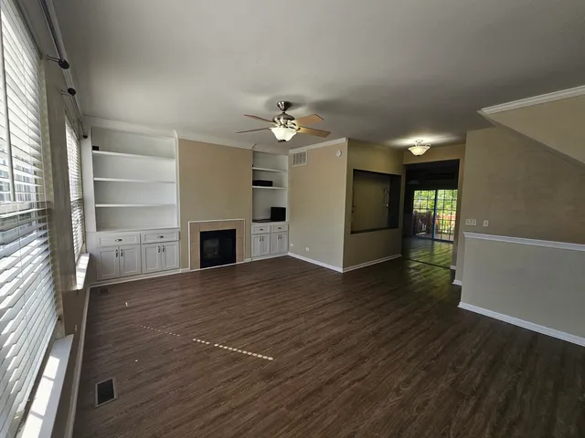 an empty room with wooden floor fireplace and windows