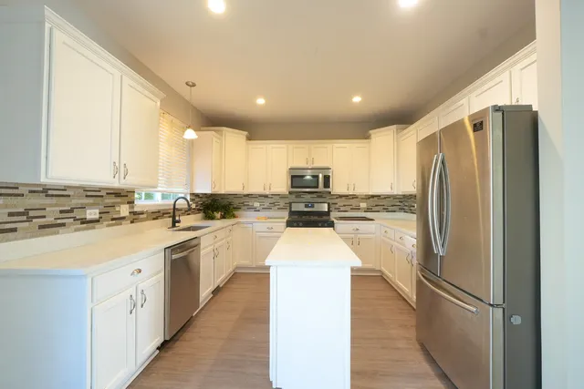 a kitchen with stainless steel appliances granite countertop a refrigerator and a stove top oven